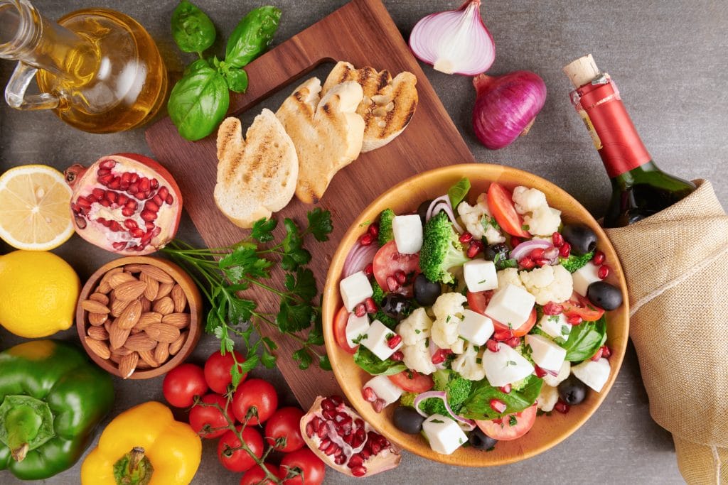 Greek salad or horiatiki with large pieces of tomatoes, cucumbers, onion, feta cheese and olives in white bowl isolated top view.