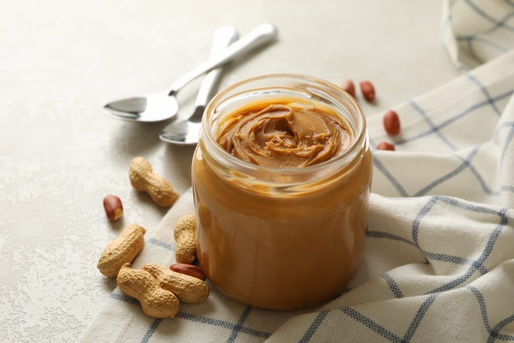 Napkin with peanut, jar of peanut butter and spoons