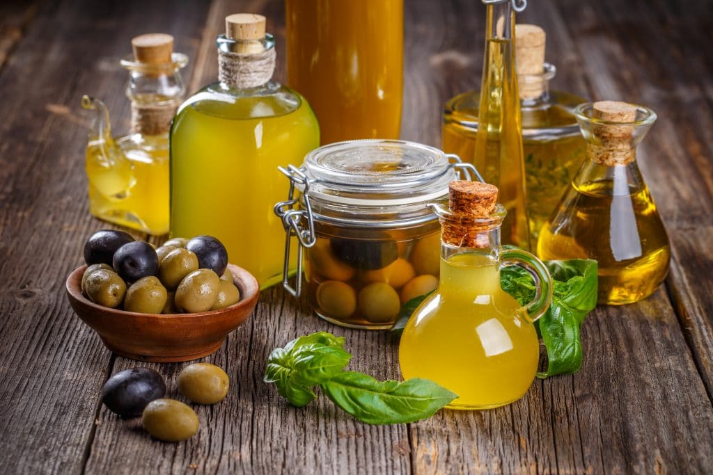 Olive oil in vintage bottles with green and black olives on rustic wooden background