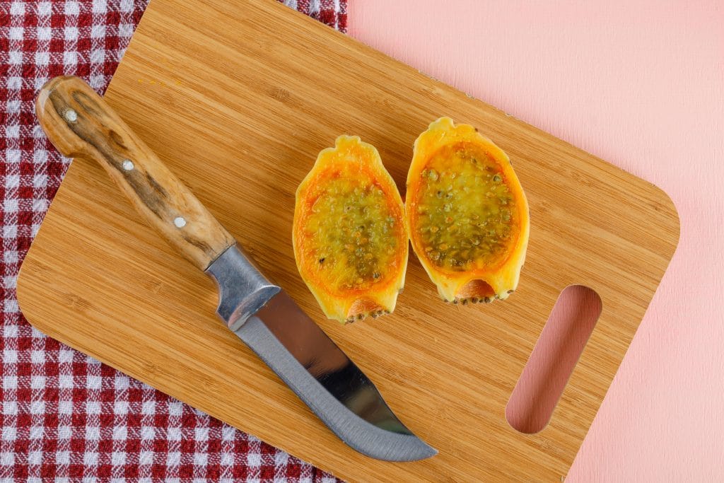 Prickly pear with cutting board, knife flat lay on pink and picnic cloth background