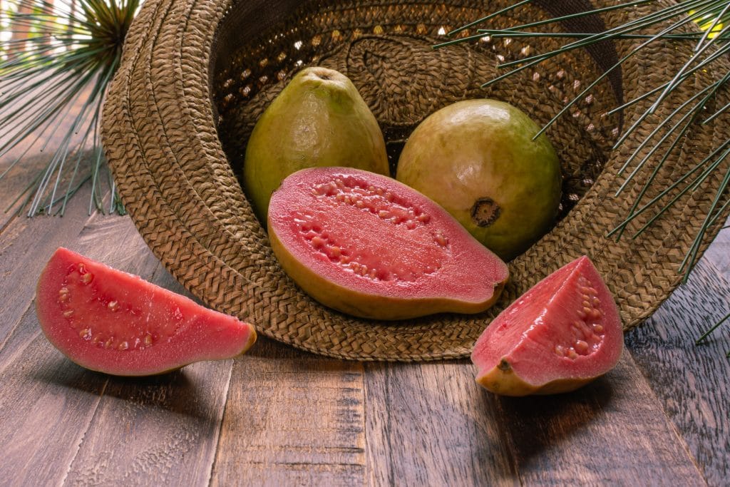 Fresh guava fruit. Two whole guava fruits and slices in traditional hat.