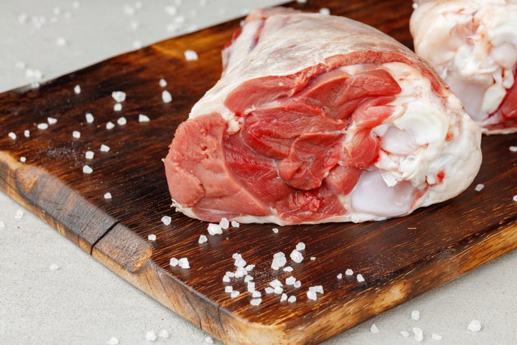 Raw lamb shanks on wooden board close up photo