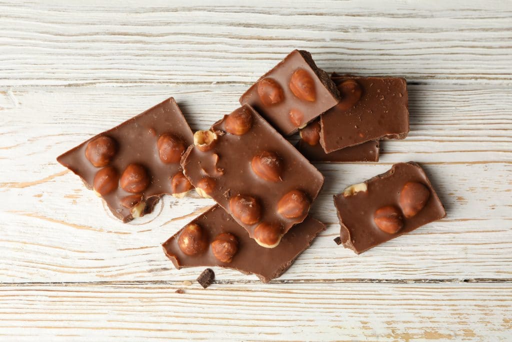 Tasty chocolate pieces on white wooden table