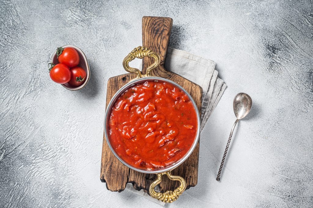 Classic Italian tomato sauce with basil for pasta and pizza in skillet. White background. Top view.