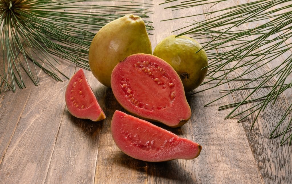 Whole guava fruits and slices over old wood