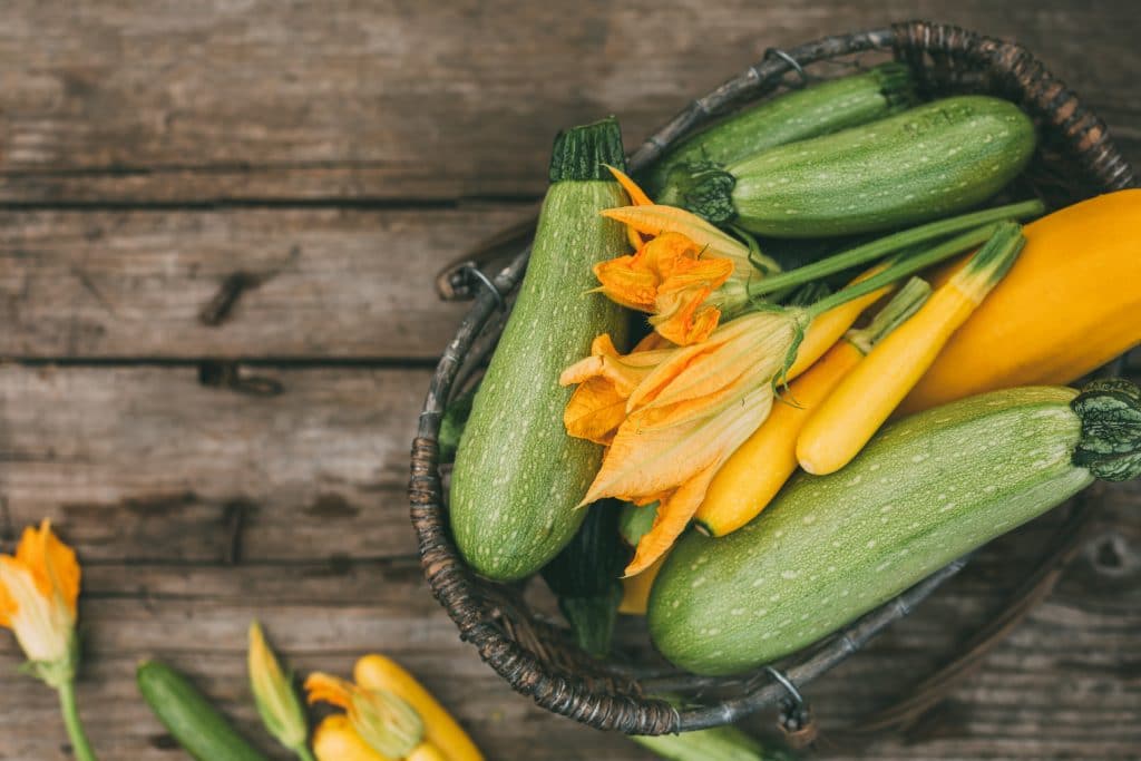 Freshly picked zucchini in a basket on a wooden table. Harvest season. Top view, selective focus.