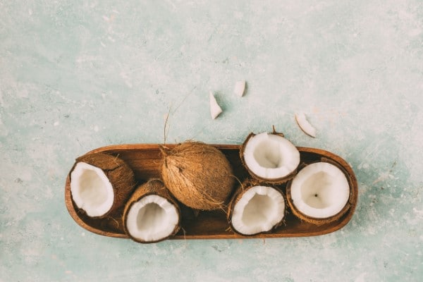 Fresh coconuts with coconut halves on a tray, top view.