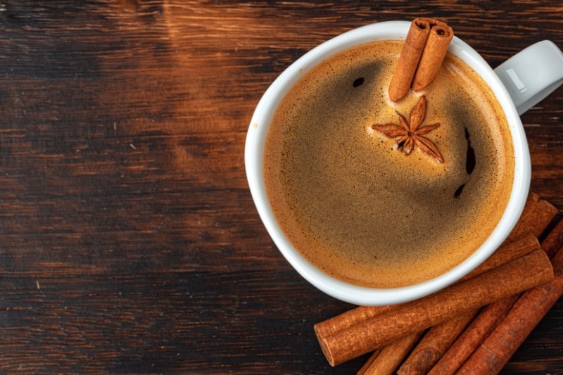 Cup of americano coffee with cinnamon on table close up