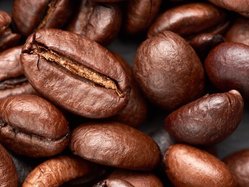 roasted grains of Robusta coffee on a black background, top view, full frame